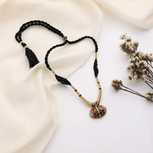 Close-up of oval stone pendant on black-thread necklace with gold detailing