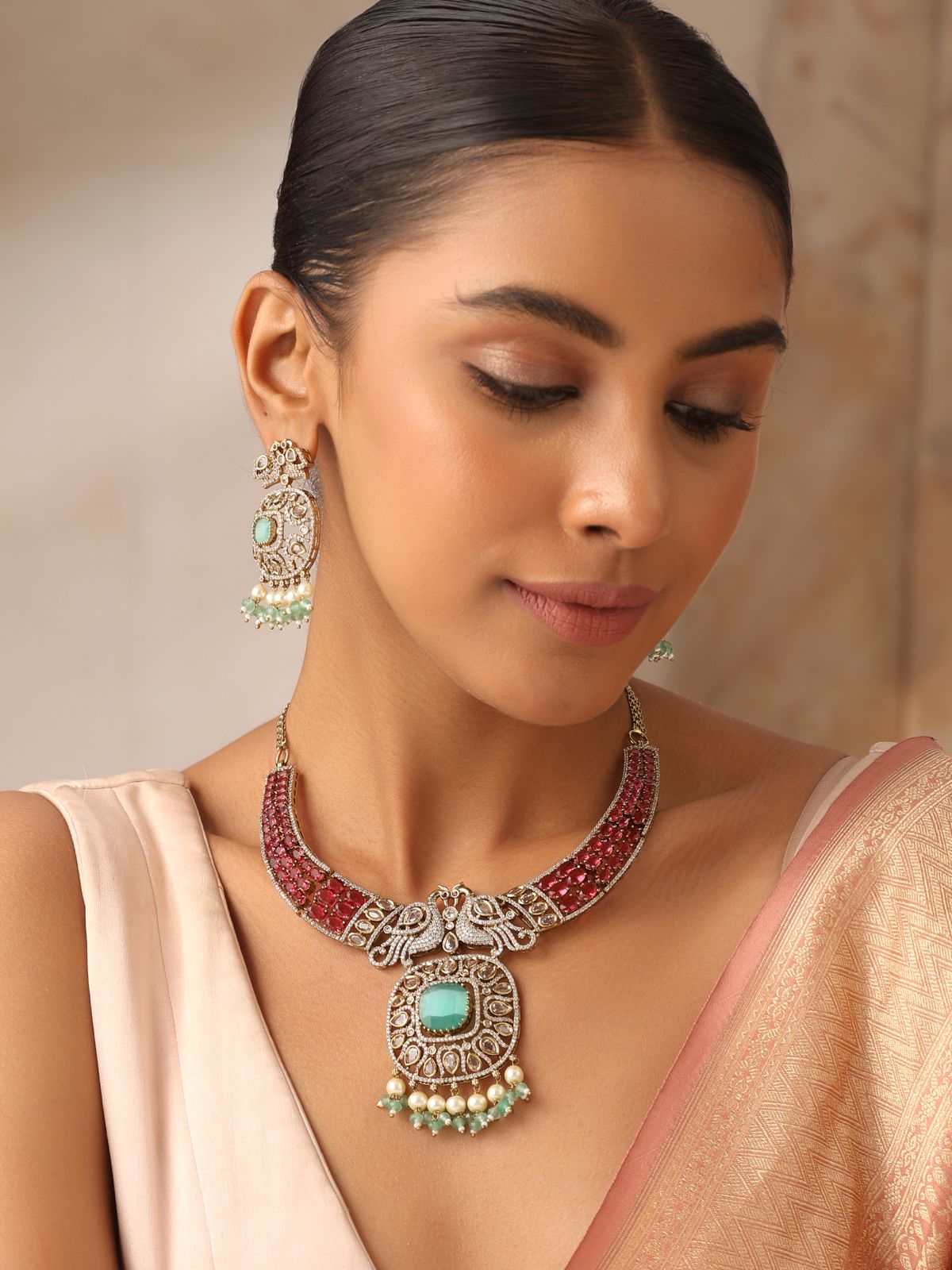 Model wearing ruby stone necklace with emerald pendant and kundan work