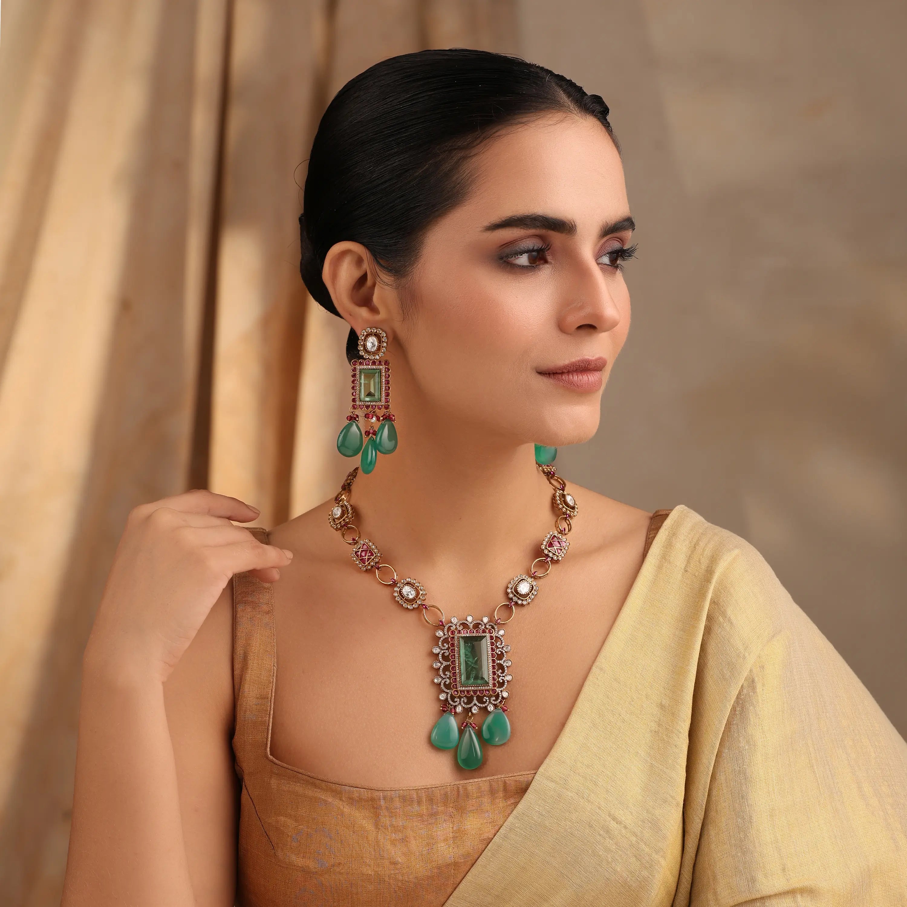 Emerald ruby Kundan necklace set with rectangular green pendant and matching earrings worn by model.
