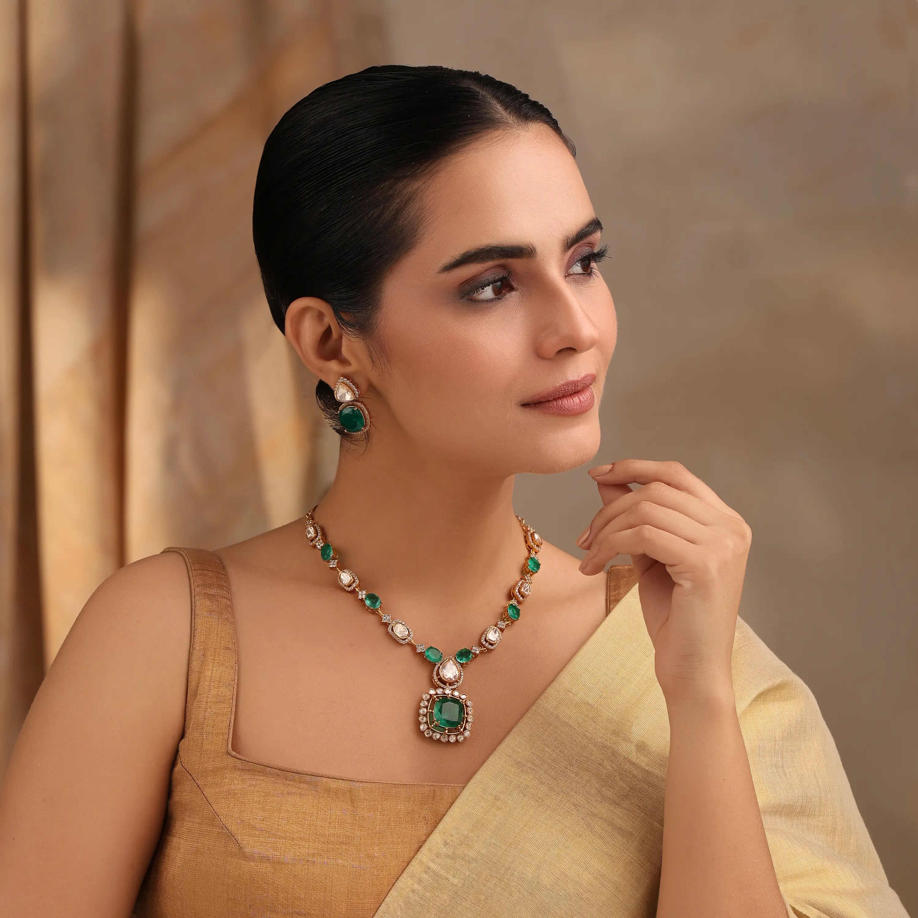 Model wearing emerald necklace set with matching earrings