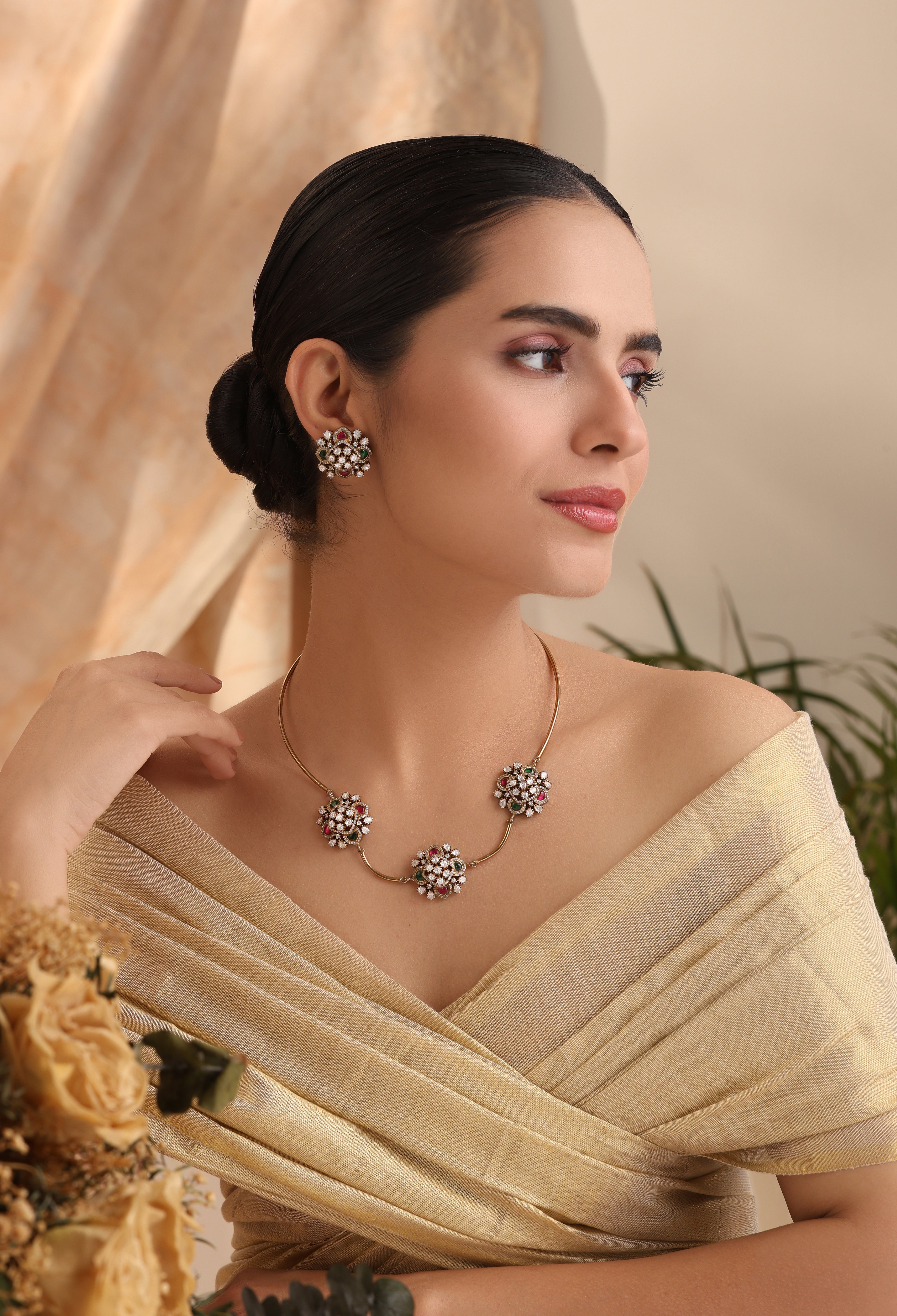 Model wearing Zahra Rosette Moissanite Hasli Set, gold-tone choker with three rosette clusters, emerald & ruby accents, matching stud earrings – MyRivaaz.
