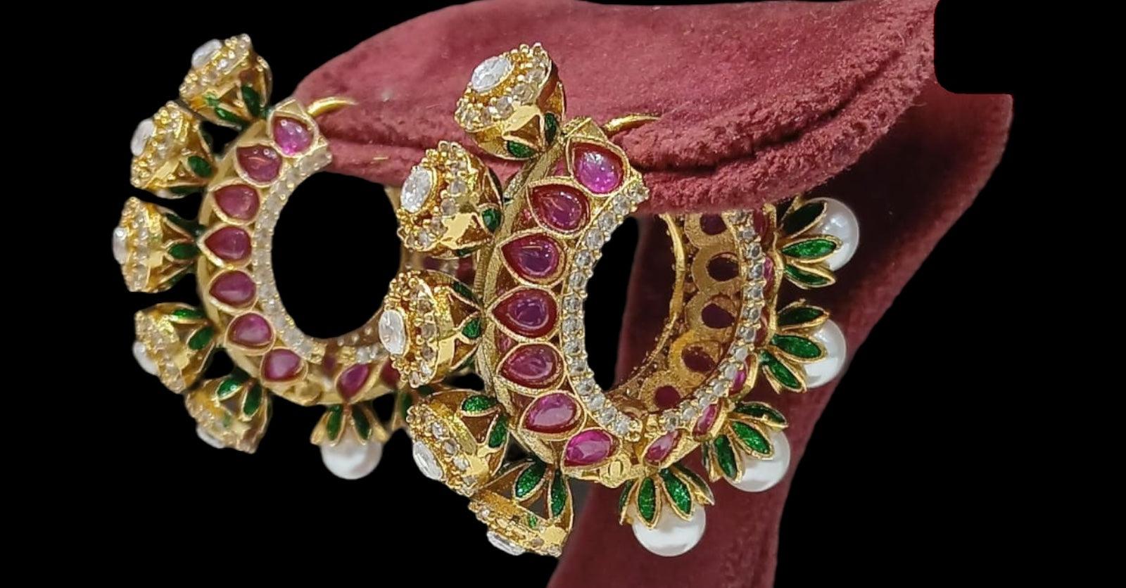 Gold-plated kundan hoop earrings with red stones, CZ accents, and pearl danglers.
