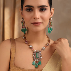 Model wearing emerald ruby Kundan necklace and earrings styled with gold blouse.