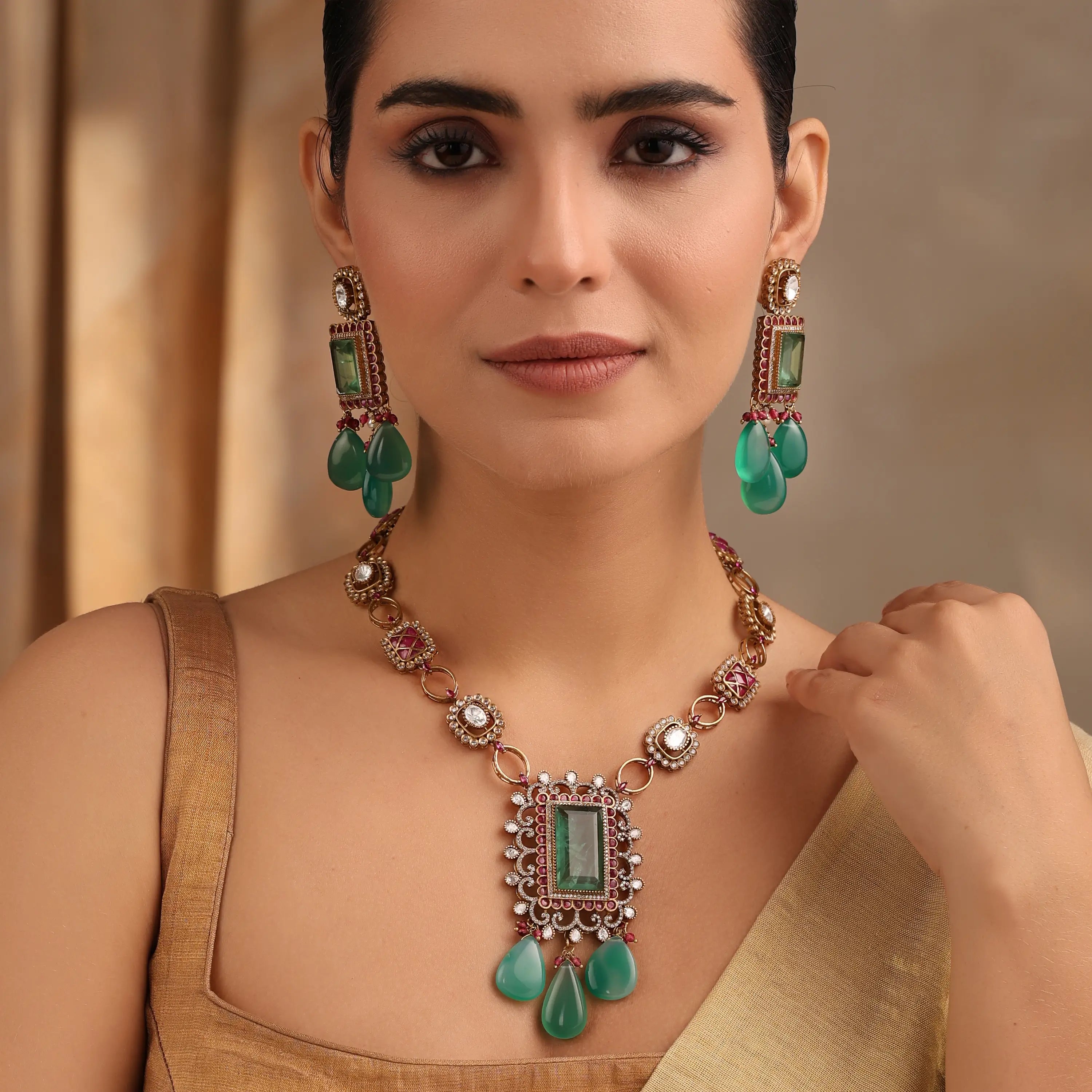 Model wearing emerald ruby Kundan necklace and earrings styled with gold blouse.