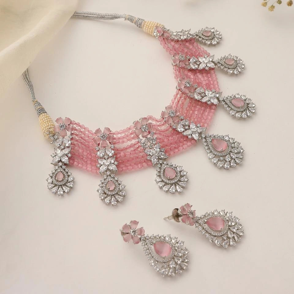 Jewelry set with pink stones and silver accents on a pink fabric background