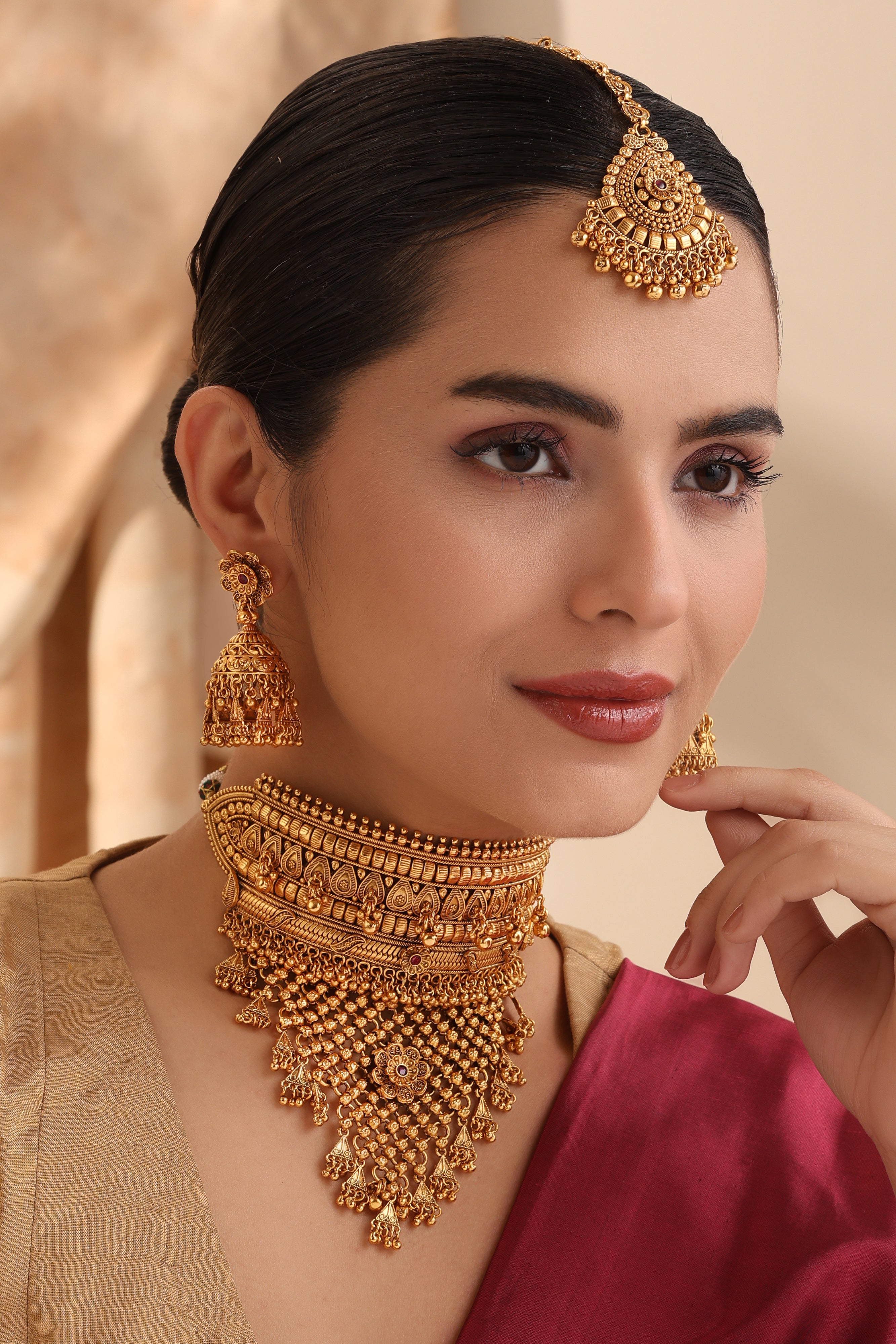 Model wearing Rajasi Antique Gold Choker, matching jhumkas and maang tikka – wedding jewelry set