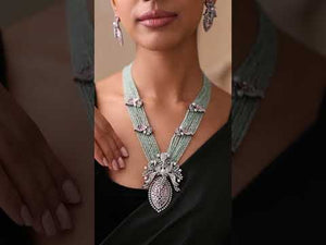 Close-up of mint beaded necklace with purple stone floral detailing on model